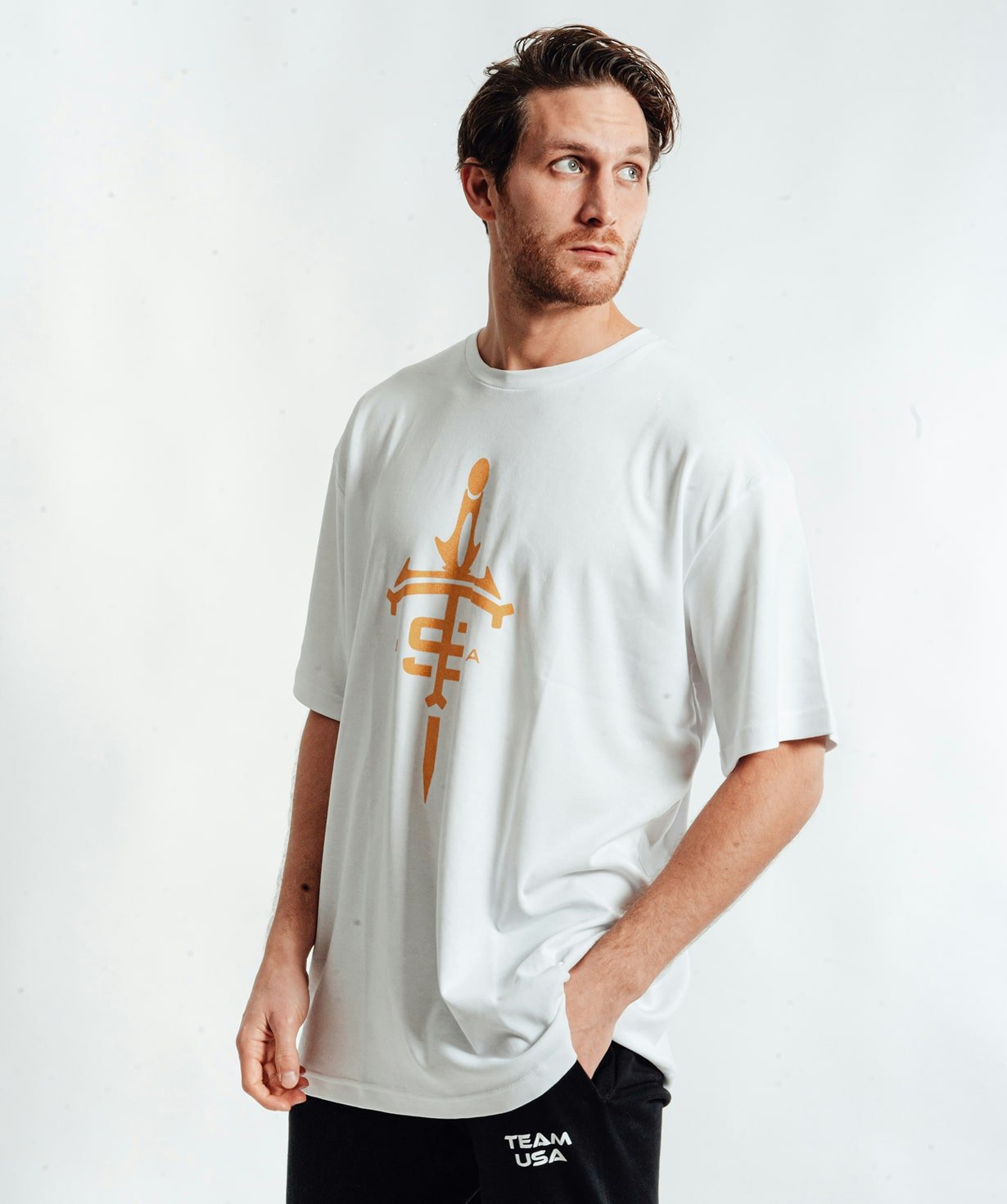 White graphic sports tee with gold emblem